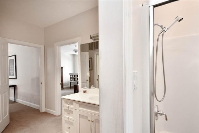 bathroom featuring walk in shower, vanity, and baseboards