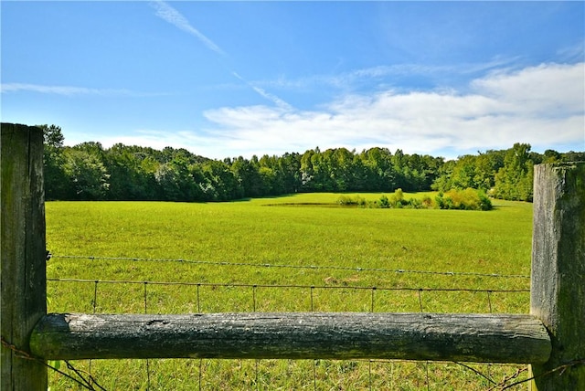 exterior space featuring a rural view, fence, and a wooded view