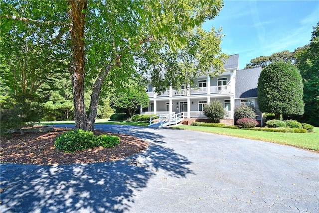 view of front of home with a balcony, covered porch, and aphalt driveway