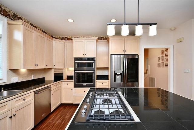 kitchen with tasteful backsplash, dark wood finished floors, dark countertops, appliances with stainless steel finishes, and pendant lighting