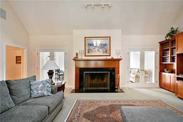 living area with a fireplace with flush hearth, lofted ceiling, french doors, and carpet