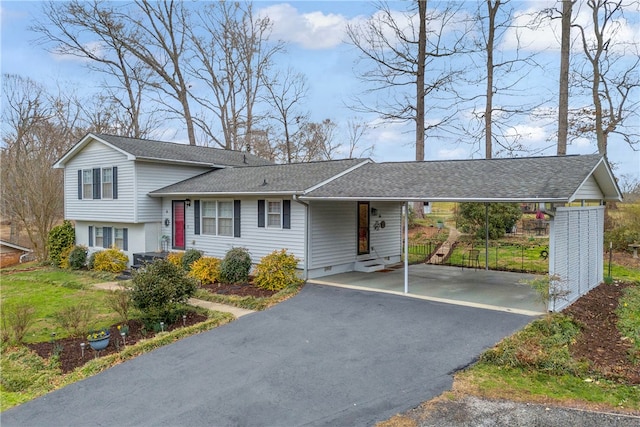 tri-level home with entry steps, an attached carport, driveway, roof with shingles, and crawl space