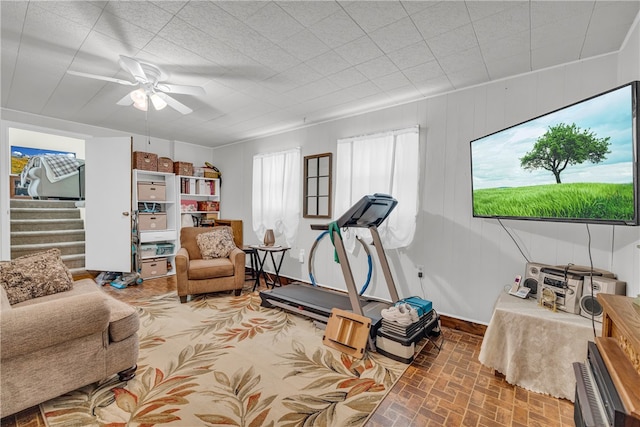 interior space featuring brick floor, stairway, and a ceiling fan