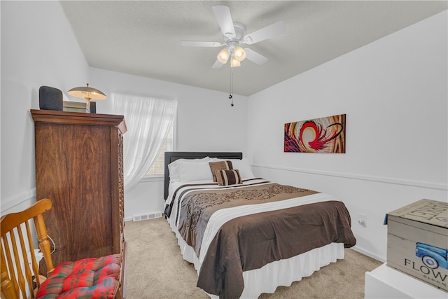 carpeted bedroom featuring visible vents, ceiling fan, a textured ceiling, and baseboards