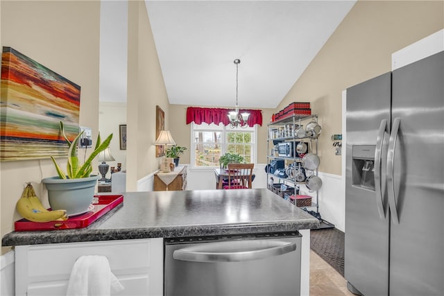 kitchen with lofted ceiling, stainless steel appliances, a peninsula, white cabinets, and dark countertops