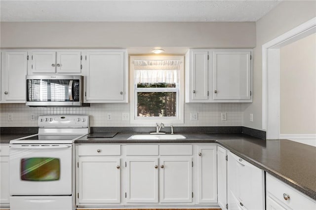 kitchen featuring dark countertops, stainless steel microwave, a sink, and white range with electric cooktop