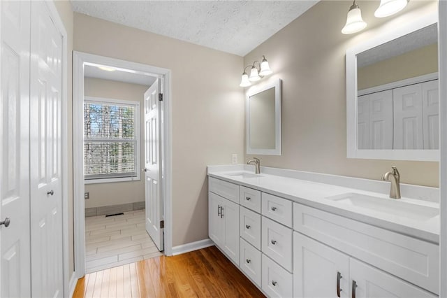 bathroom featuring double vanity, a textured ceiling, a sink, and wood finished floors