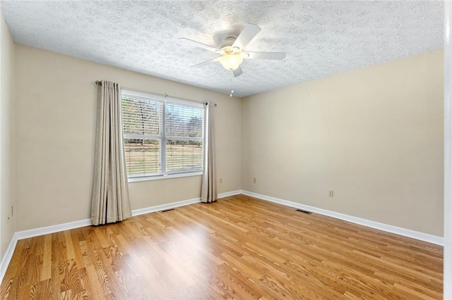 empty room featuring light wood-style floors, visible vents, a textured ceiling, and a ceiling fan