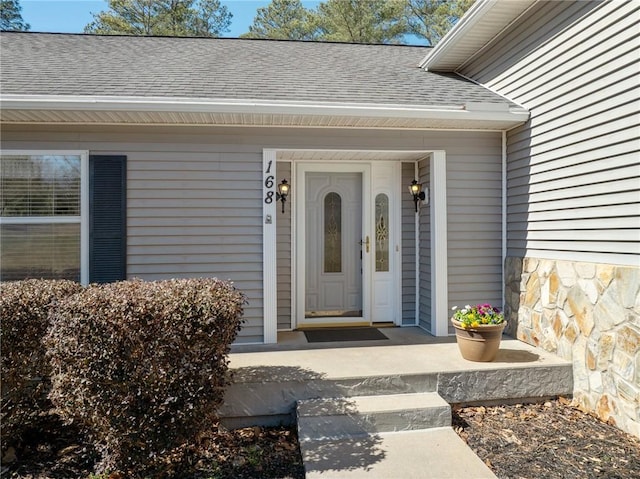 entrance to property with stone siding and roof with shingles