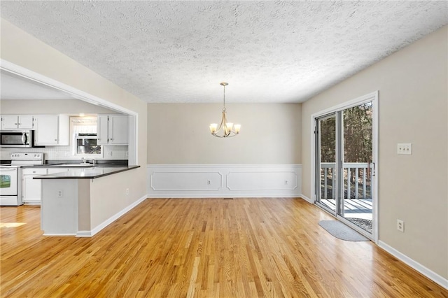 kitchen featuring a healthy amount of sunlight, an inviting chandelier, electric range, and stainless steel microwave