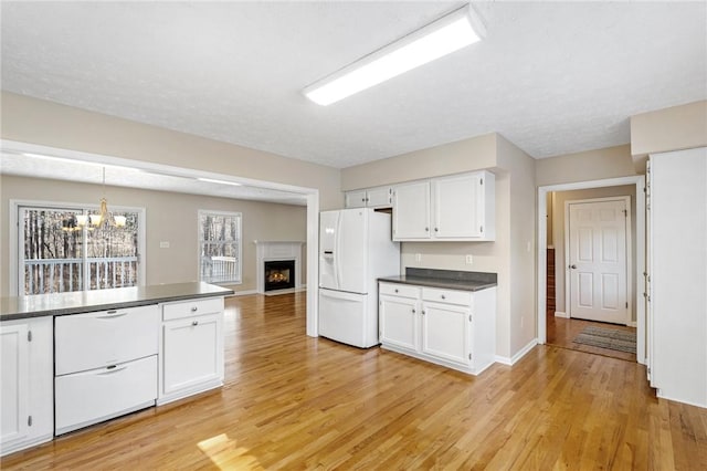 kitchen featuring dark countertops, white refrigerator with ice dispenser, white cabinetry, and light wood finished floors