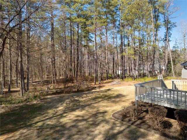 view of yard featuring a wooded view and a wooden deck