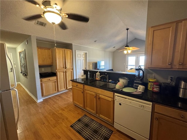 kitchen with white dishwasher, a sink, visible vents, freestanding refrigerator, and light wood finished floors