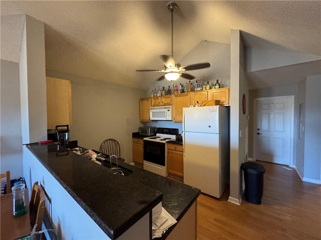 kitchen with white appliances, a ceiling fan, dark countertops, lofted ceiling, and a peninsula