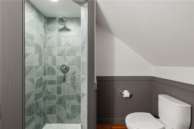 bathroom featuring toilet, a wainscoted wall, and a tile shower