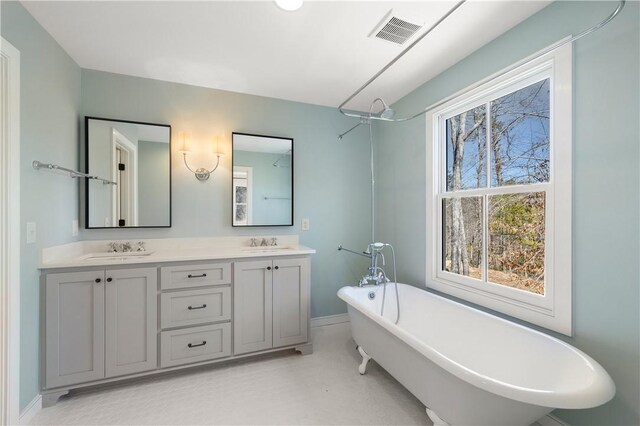 full bathroom with a freestanding tub, visible vents, a sink, and double vanity