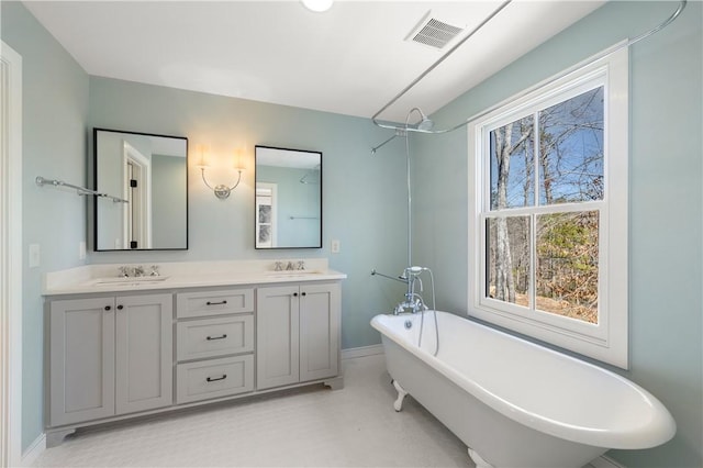 full bath with visible vents, a sink, a freestanding bath, and double vanity