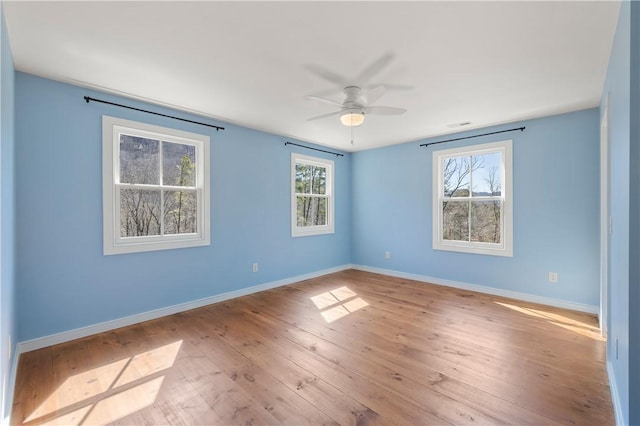 spare room featuring wood finished floors, baseboards, and ceiling fan