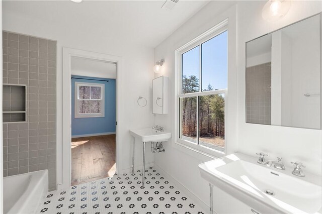 bathroom with a tub, a sink, and baseboards