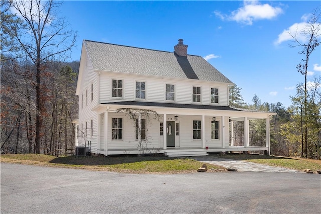 view of front facade featuring covered porch, a shingled roof, a chimney, and central air condition unit