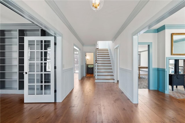 entryway with a wainscoted wall, stairway, crown molding, and hardwood / wood-style floors