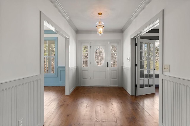 entryway with wainscoting, wood-type flooring, and crown molding