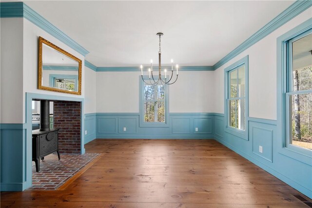 dining room with visible vents, ornamental molding, wood-type flooring, a wood stove, and an inviting chandelier