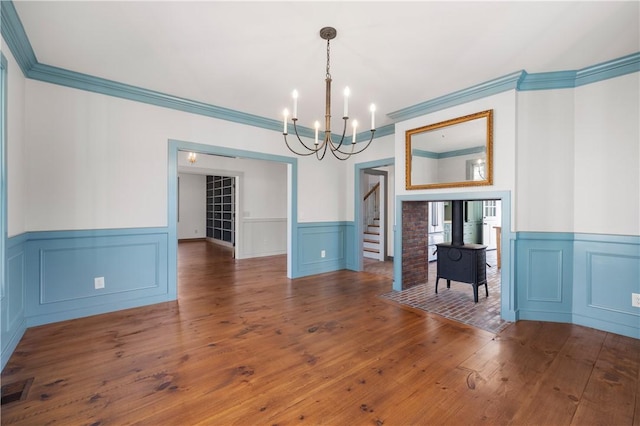 unfurnished dining area featuring a wainscoted wall, a notable chandelier, visible vents, and wood-type flooring