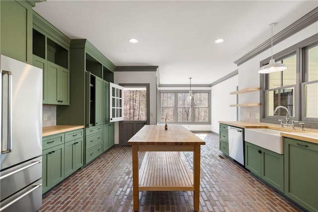 kitchen featuring open shelves, green cabinets, appliances with stainless steel finishes, a sink, and butcher block countertops