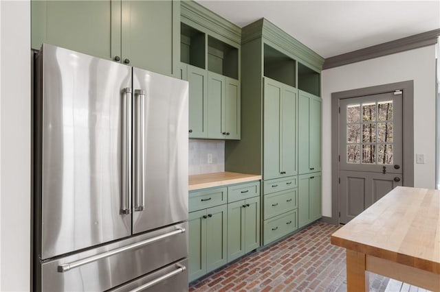 kitchen with high quality fridge, brick floor, green cabinetry, open shelves, and crown molding