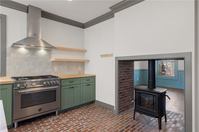 kitchen with butcher block counters, a wood stove, green cabinetry, high end range, and extractor fan