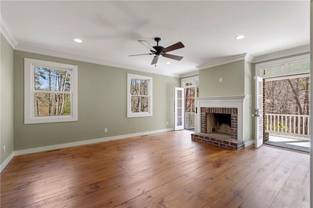 unfurnished living room with baseboards, hardwood / wood-style floors, crown molding, a fireplace, and recessed lighting