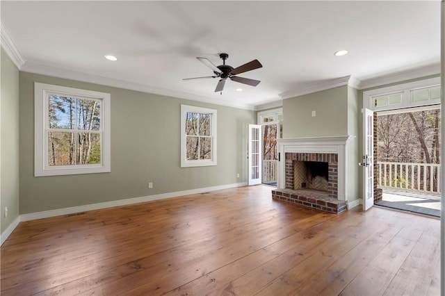 unfurnished living room featuring baseboards, ornamental molding, a fireplace, a ceiling fan, and wood-type flooring
