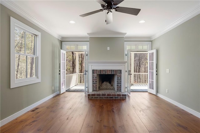 unfurnished living room featuring ornamental molding, a fireplace, baseboards, and hardwood / wood-style flooring