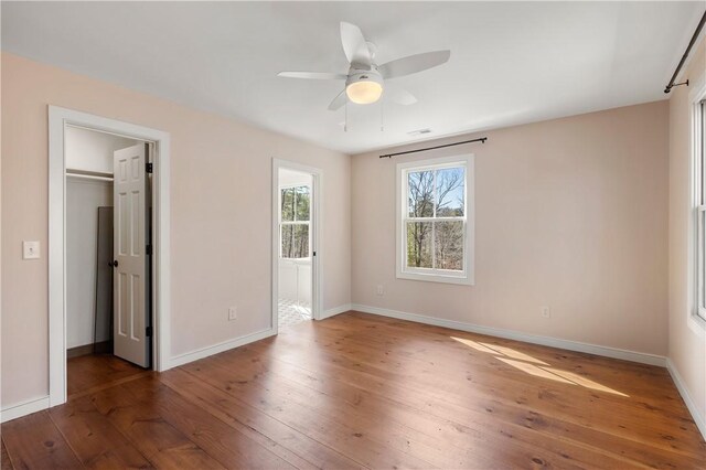 interior space with ceiling fan, visible vents, baseboards, and hardwood / wood-style floors