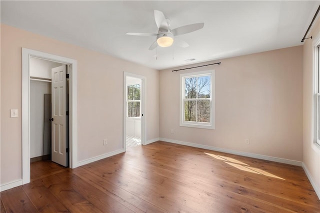 unfurnished bedroom with hardwood / wood-style flooring, a spacious closet, baseboards, and a closet