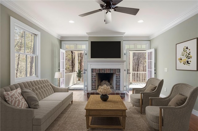 living room featuring a brick fireplace, crown molding, and wood finished floors
