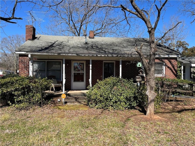 view of front of home with a chimney and brick siding