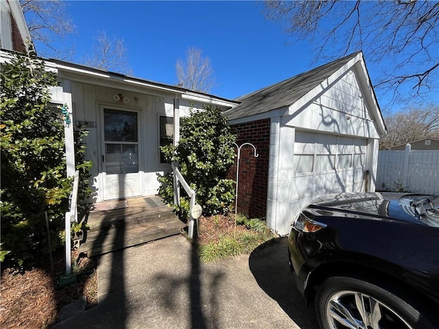 view of front facade featuring a garage, brick siding, board and batten siding, and an outdoor structure