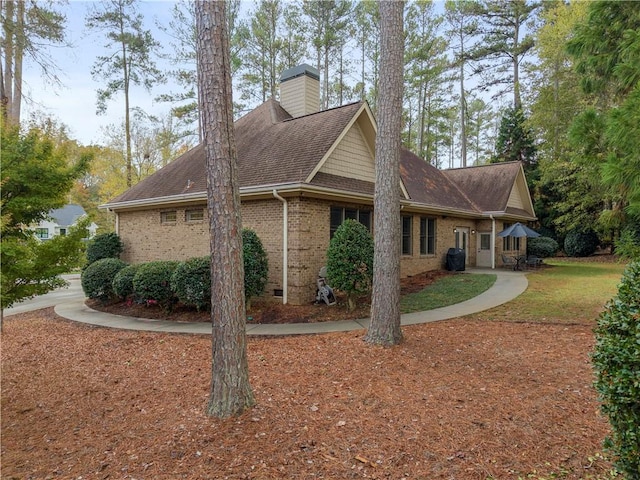 view of side of property featuring brick siding, a chimney, and roof with shingles