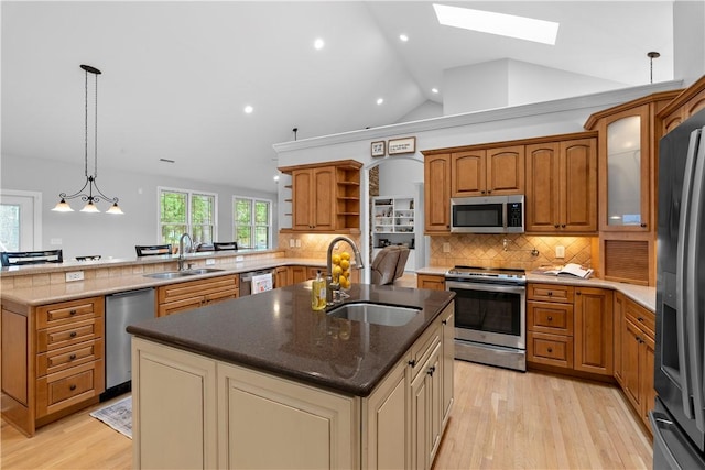 kitchen featuring stainless steel appliances, a sink, an island with sink, and open shelves