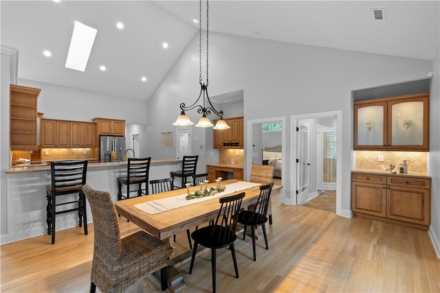 dining room with light wood-style flooring, recessed lighting, a skylight, visible vents, and baseboards