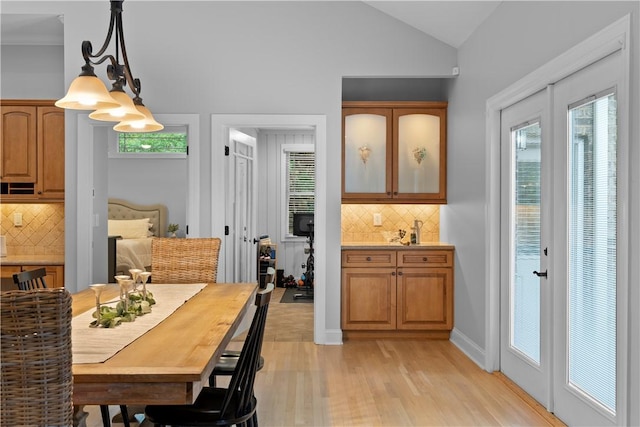 dining space with baseboards, vaulted ceiling, and light wood finished floors