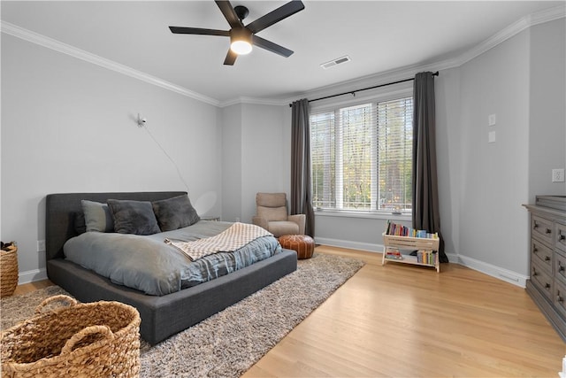 bedroom featuring baseboards, visible vents, a ceiling fan, crown molding, and light wood-type flooring