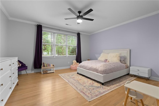 bedroom featuring ornamental molding, light wood finished floors, visible vents, and baseboards