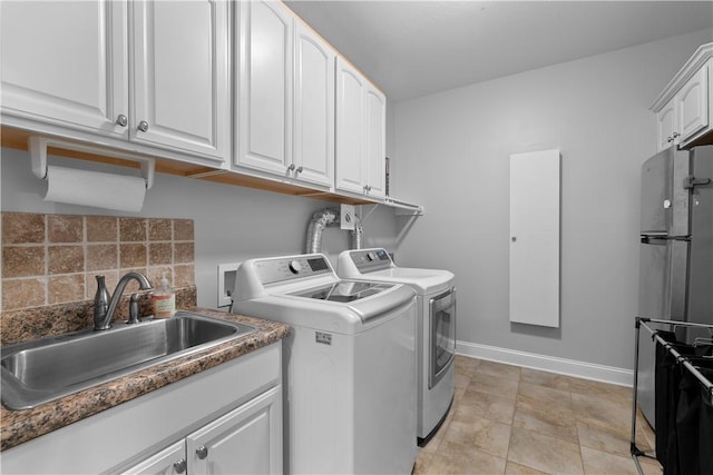 laundry room featuring washing machine and dryer, a sink, and baseboards