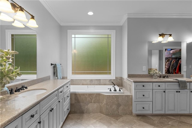 full bath featuring a garden tub, two vanities, a sink, ornamental molding, and a walk in closet