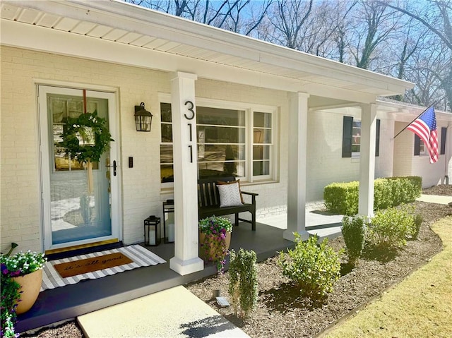 view of exterior entry with covered porch and brick siding