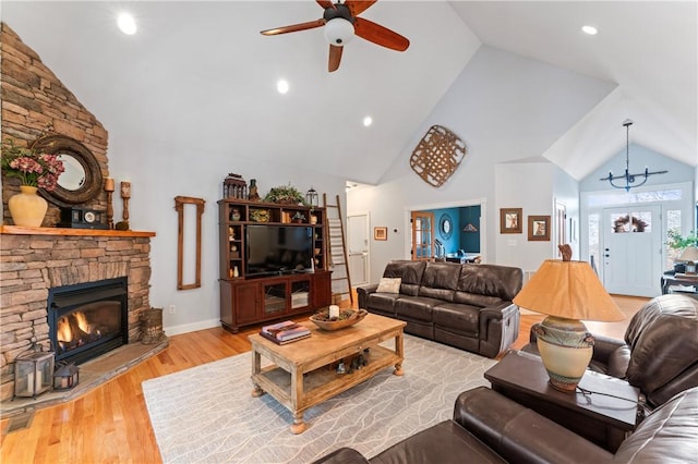 living area with a fireplace, a ceiling fan, wood finished floors, high vaulted ceiling, and baseboards