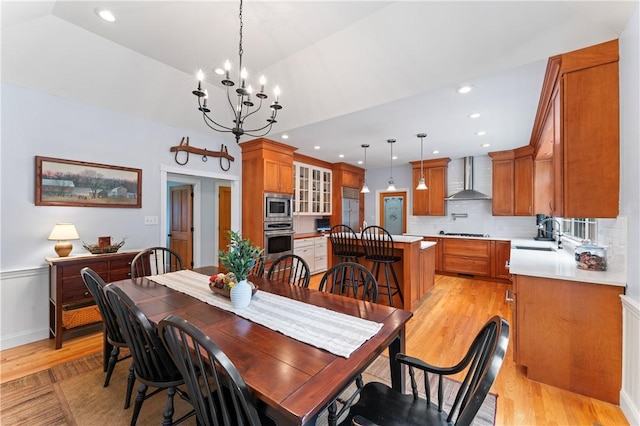 dining space with a notable chandelier, light wood finished floors, lofted ceiling, and recessed lighting